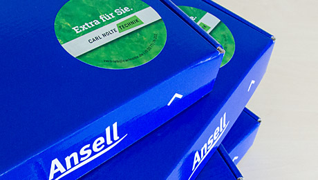 Jetzt Gratis-Überraschungsbox mit HyFlex 11-840 anfordern! gestapelte blaue Pappkartons mit Logo von Ansell und einem grünen, runden Aufkleber "Extra für Sie"