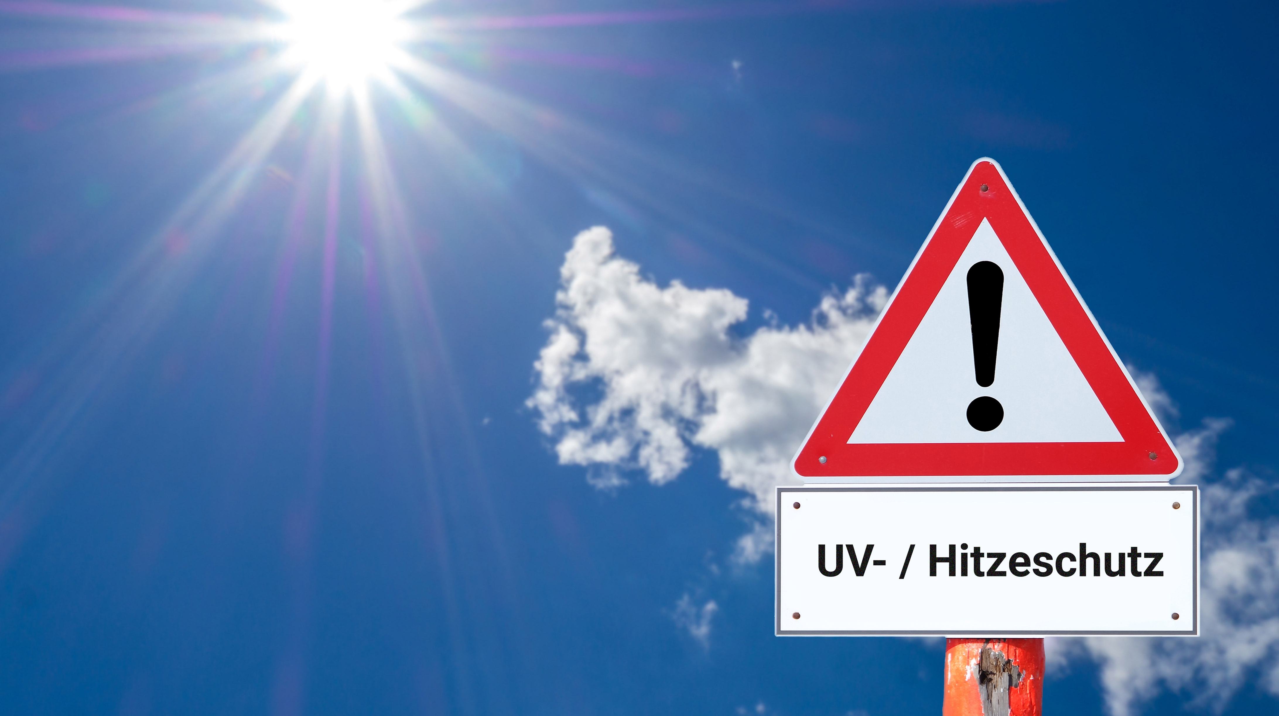 Blauer Himmel mit gleißender Sonne und Warnschild mit Text "UV-/Hitzeschutz