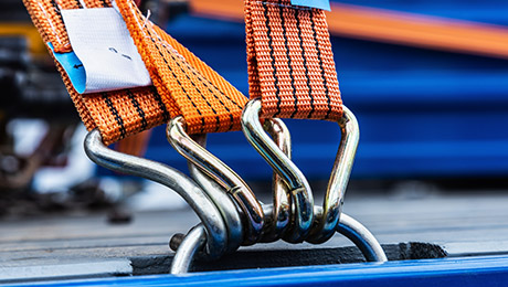 Jetzt Sachkunde-Seminar buchen! Orange Zurrgurte mit Haken vor blauer Plane